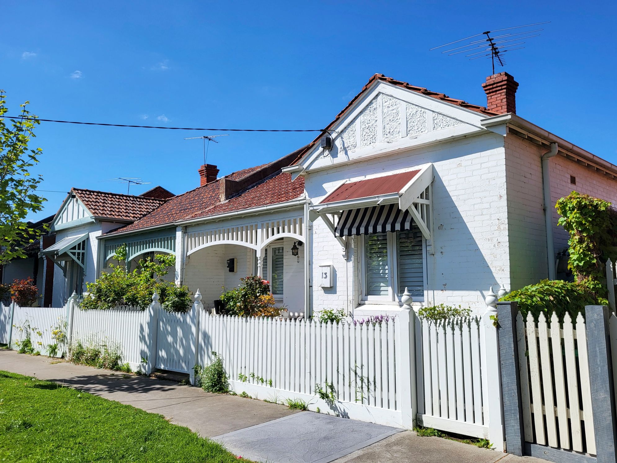 Brick home with a white picket fence on a sunny suburban street