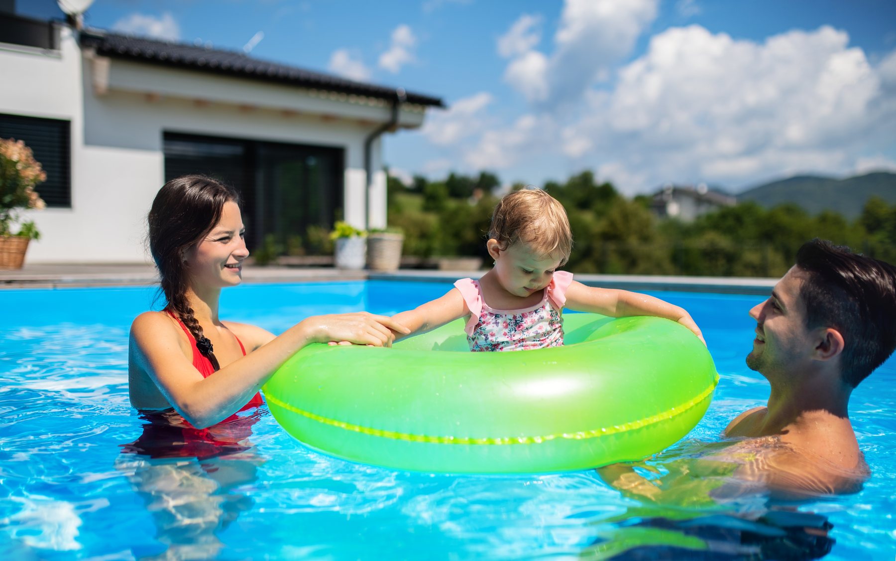 Family in a backyard swimming pool at home
